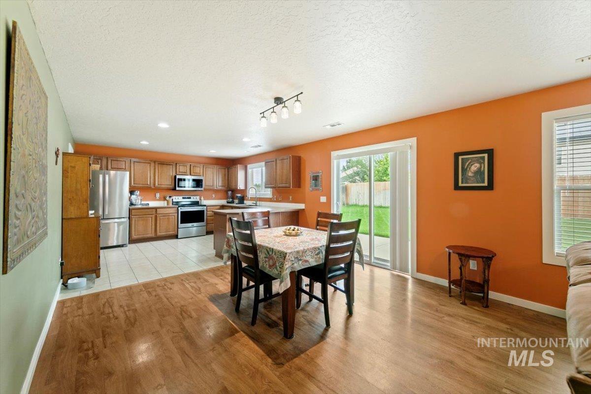 Dining room featuring a textured ceiling, light wood finished floors, and rail lighting