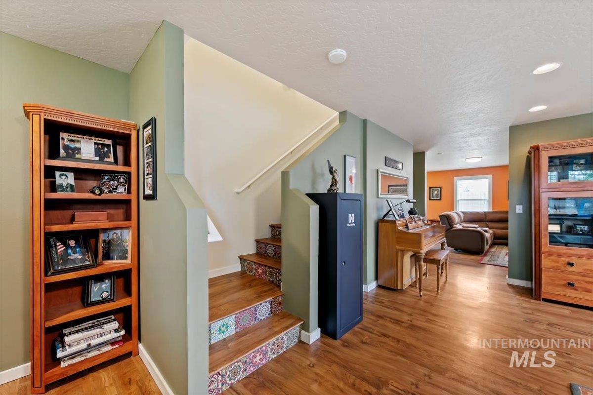Stairway with wood finished floors, a textured ceiling, and recessed lighting
