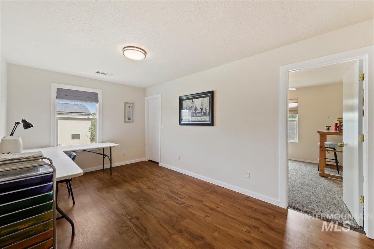 Office space featuring dark wood finished floors, a textured ceiling, and healthy amount of natural light