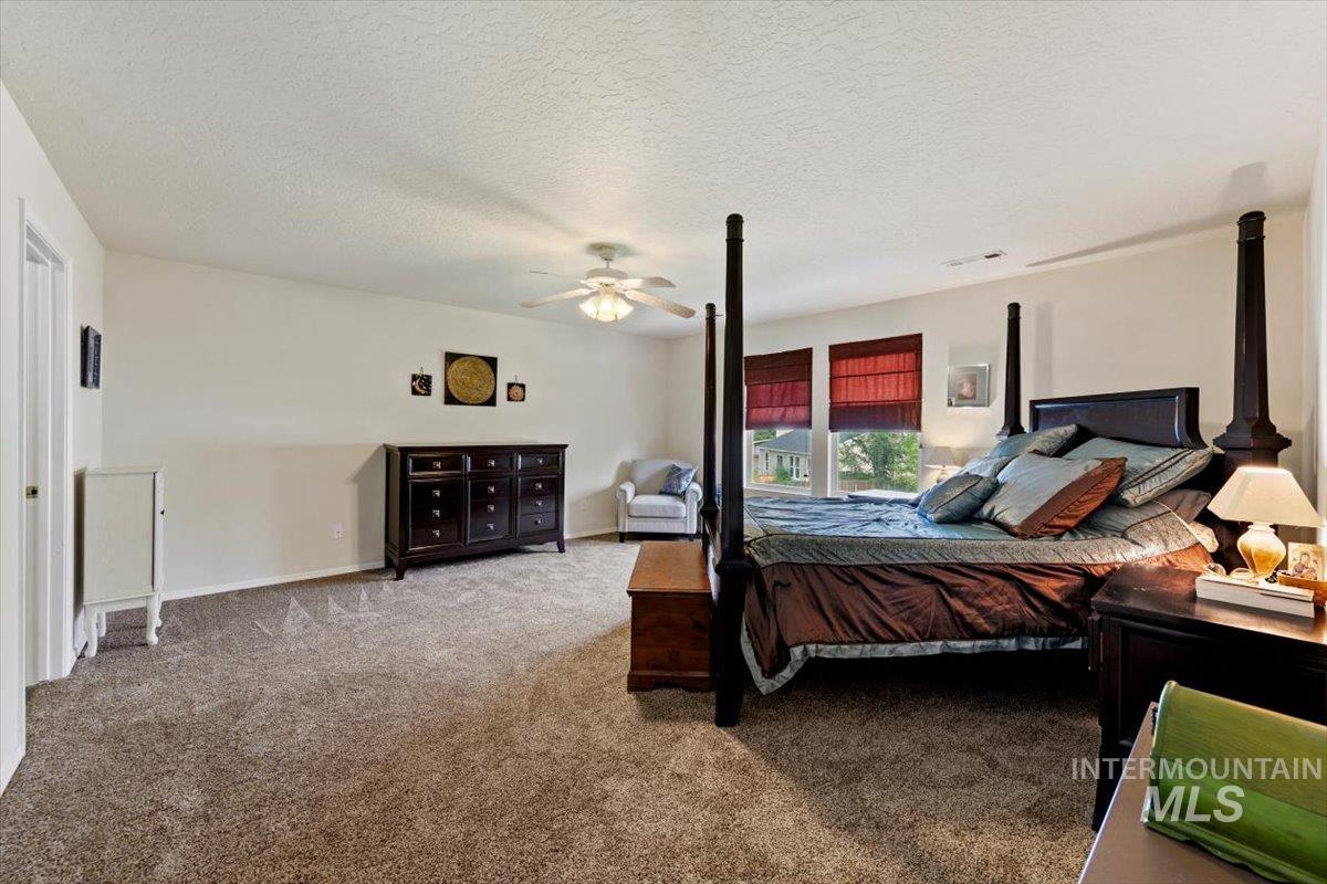 Bedroom with carpet flooring, a textured ceiling, and ceiling fan