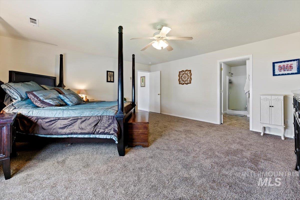 Carpeted bedroom with ceiling fan and baseboards