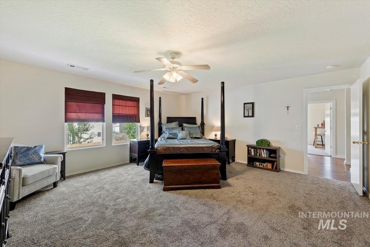 Carpeted bedroom featuring a textured ceiling and ceiling fan
