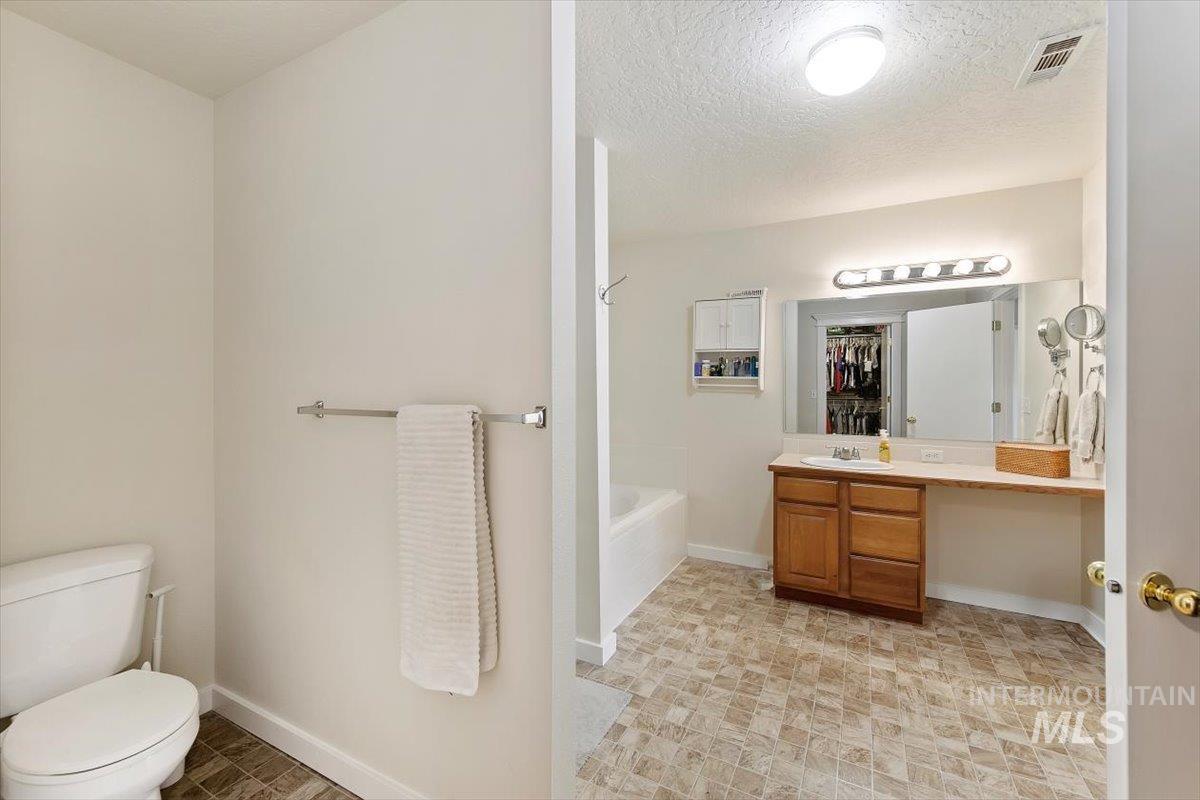Full bath featuring vanity,  shower combination, a textured ceiling, and a spacious closet