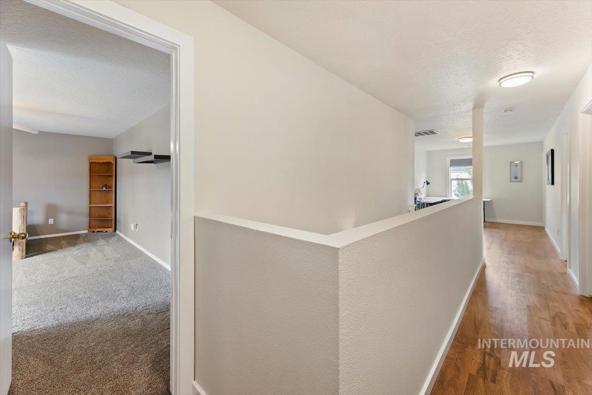 Hall featuring a textured ceiling and an upstairs landing