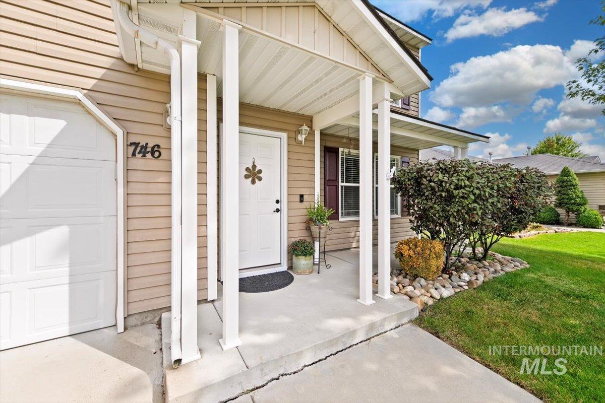 View of exterior entry featuring a porch, board and batten siding, and a lawn