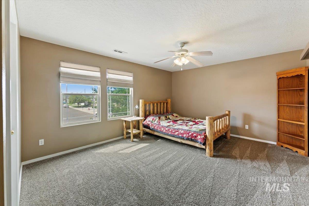 Bedroom with a textured ceiling, carpet floors, and a ceiling fan