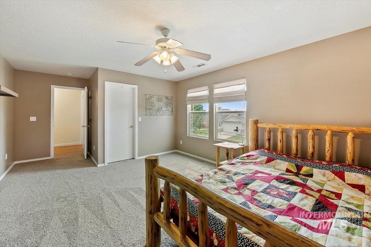 Carpeted bedroom with a textured ceiling and a ceiling fan
