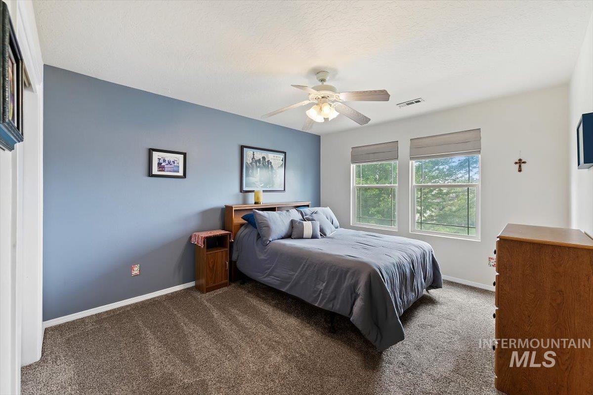 Carpeted bedroom featuring a ceiling fan and a textured ceiling