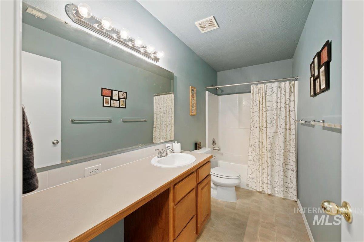 Full bath with shower / bath combo, vanity, and a textured ceiling