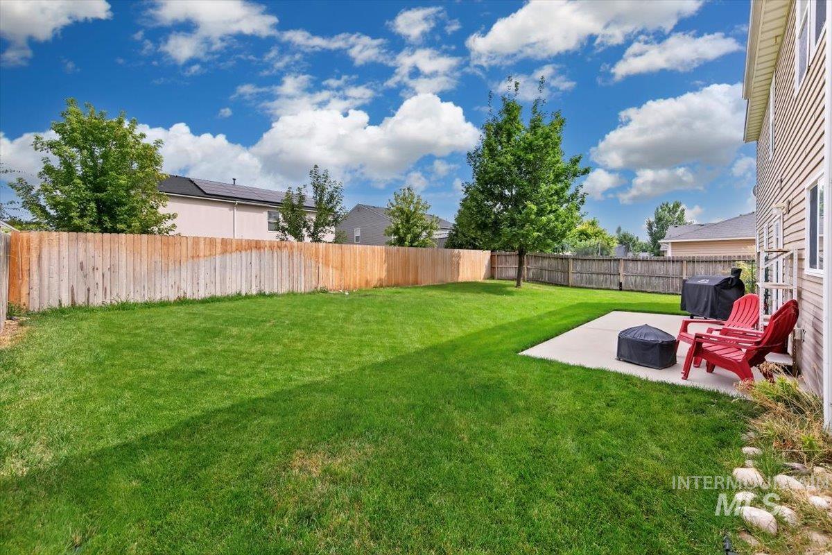 Fenced backyard featuring a fire pit and a patio