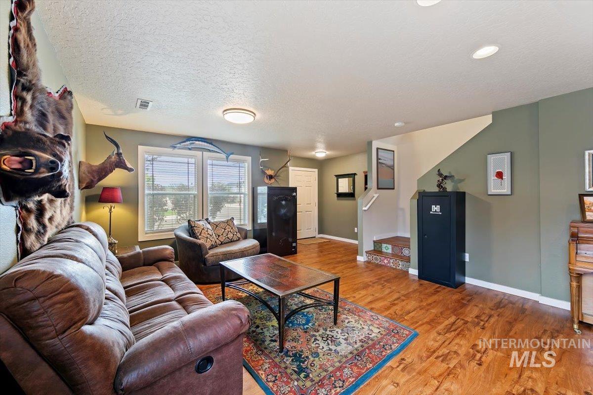 Living room with light wood finished floors, a textured ceiling, and stairway