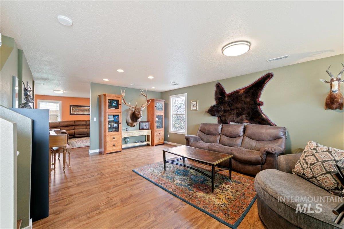 Living room with light wood finished floors, plenty of natural light, a textured ceiling, and recessed lighting