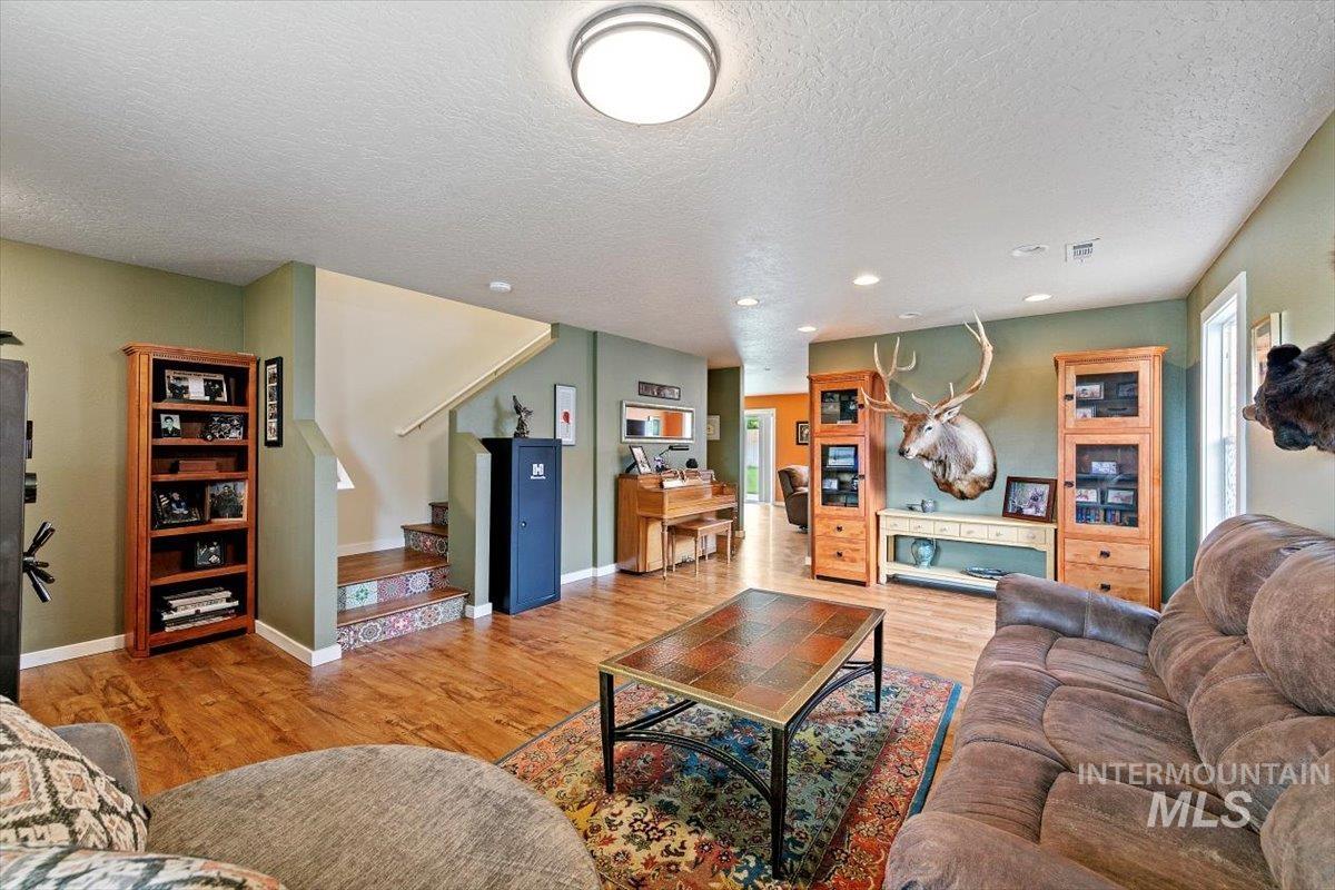 Living room featuring light wood finished floors, stairway, a textured ceiling, and recessed lighting