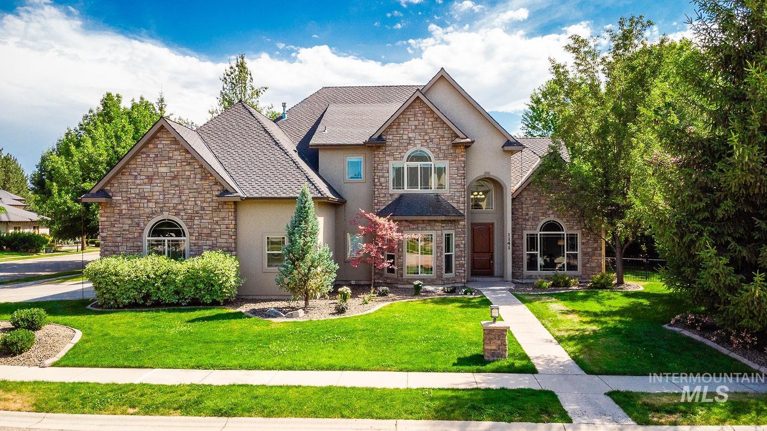 View of front of home featuring stone siding, a front lawn, stucco siding, and roof with shingles