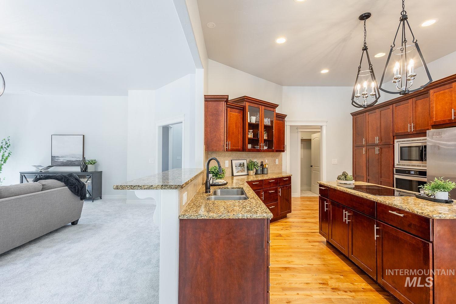 Kitchen with decorative light fixtures, a peninsula, glass insert cabinets, open floor plan, and recessed lighting