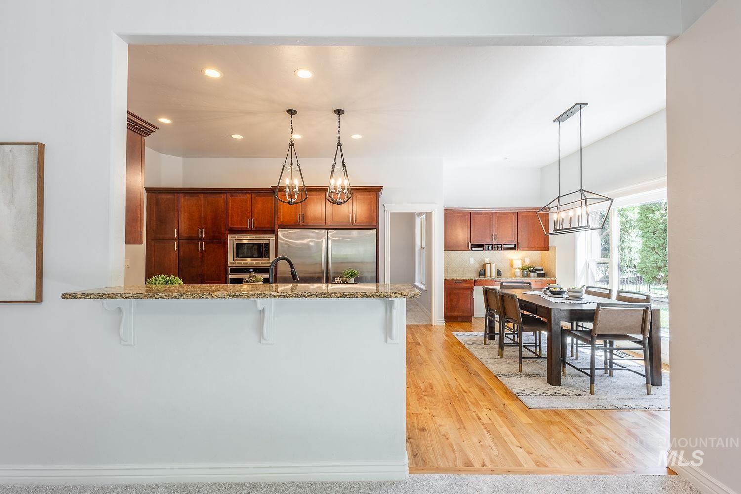 Kitchen featuring a breakfast bar, backsplash, a peninsula, recessed lighting, and brown cabinetry