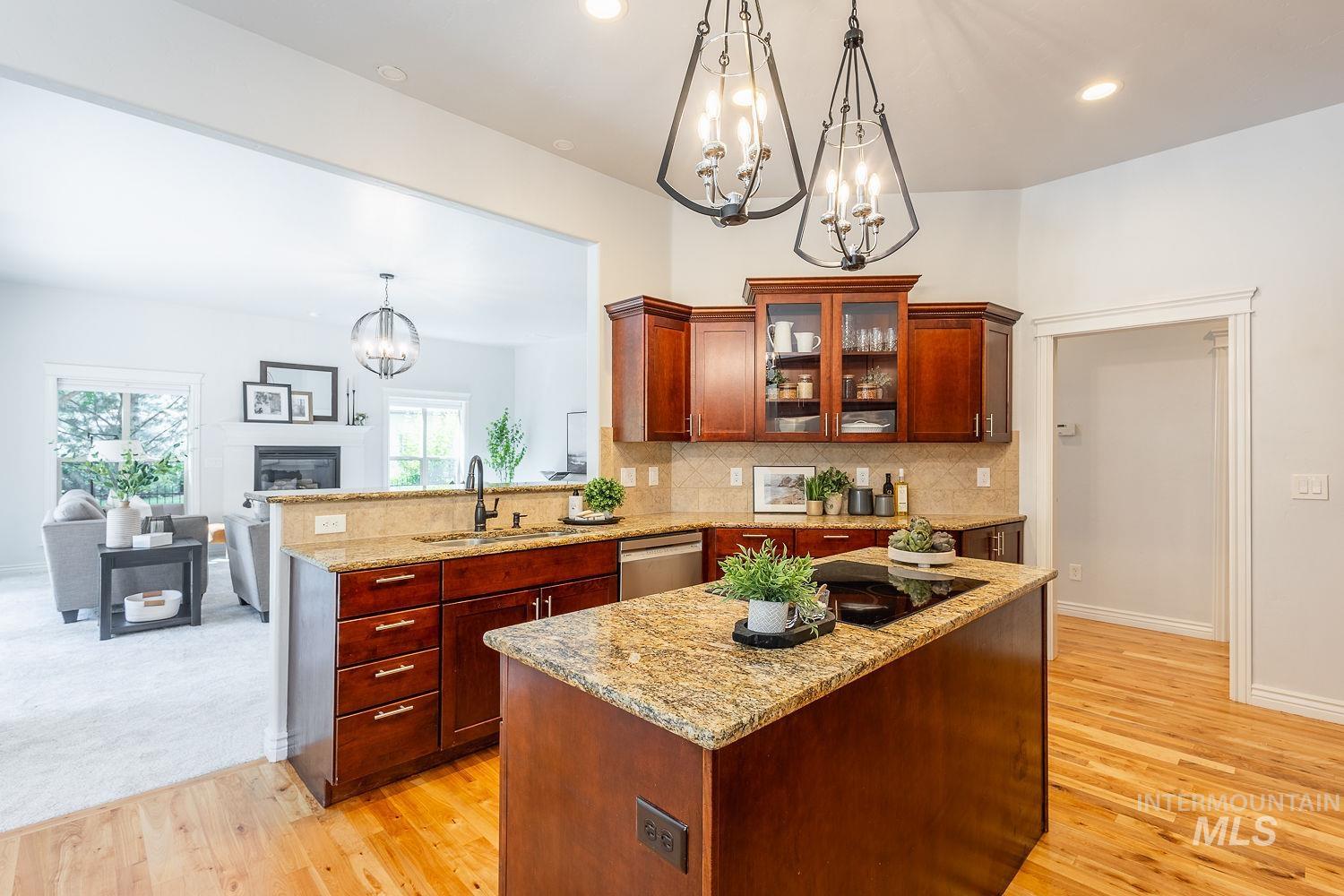 Kitchen featuring a chandelier, glass insert cabinets, backsplash, hanging light fixtures, and a kitchen island