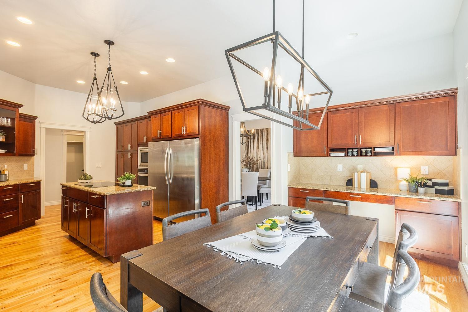 Kitchen featuring backsplash, a chandelier, light stone counters, appliances with stainless steel finishes, and light wood-style flooring