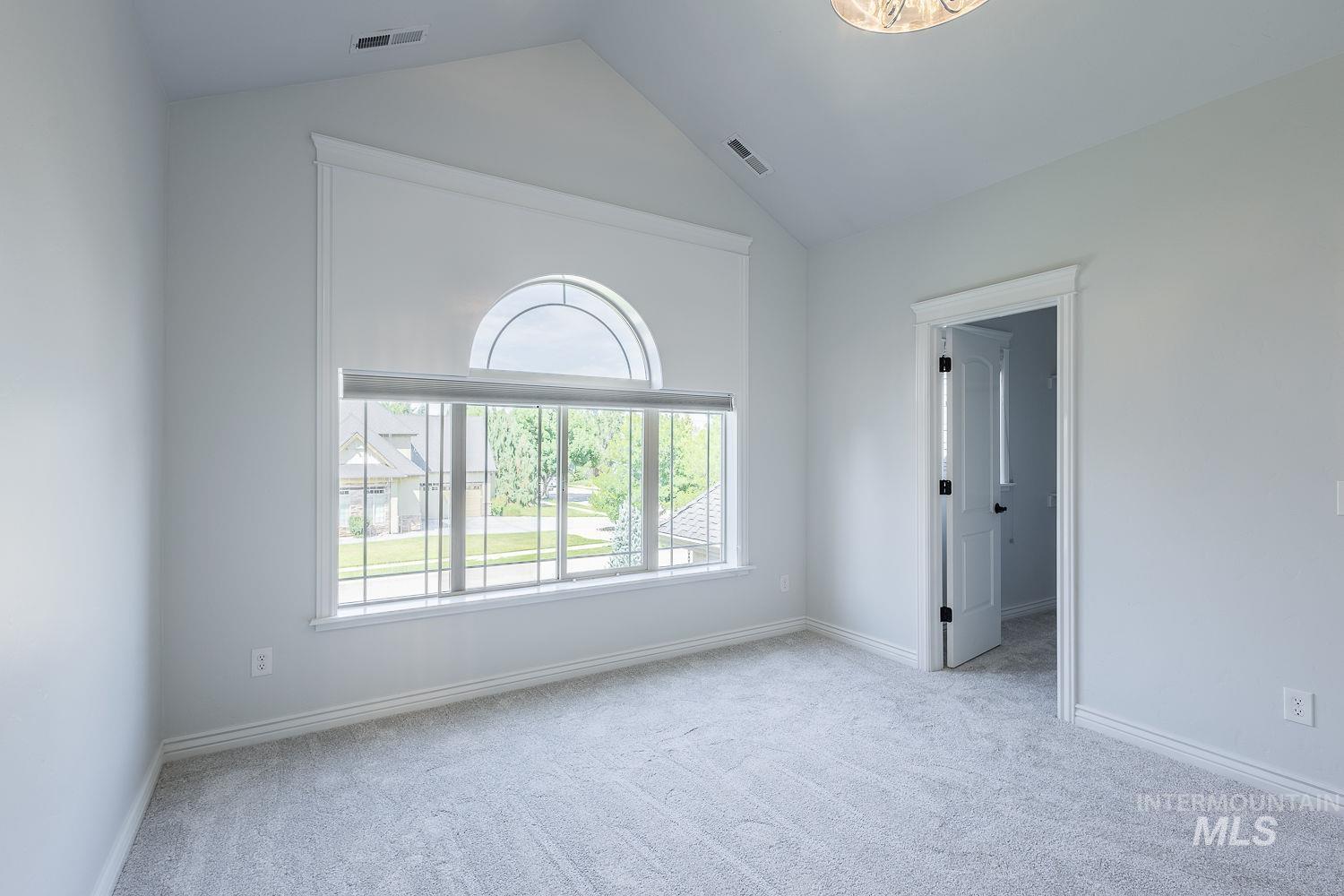 Spare room featuring light carpet and vaulted ceiling