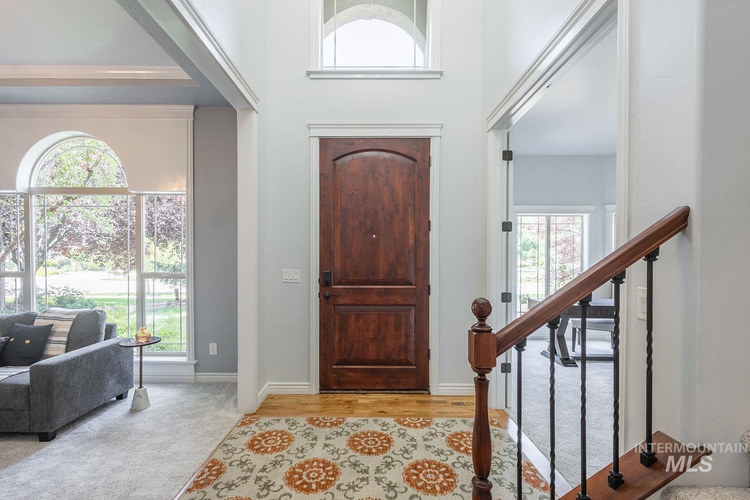 Entrance foyer with a towering ceiling, light colored carpet, and light wood-style flooring