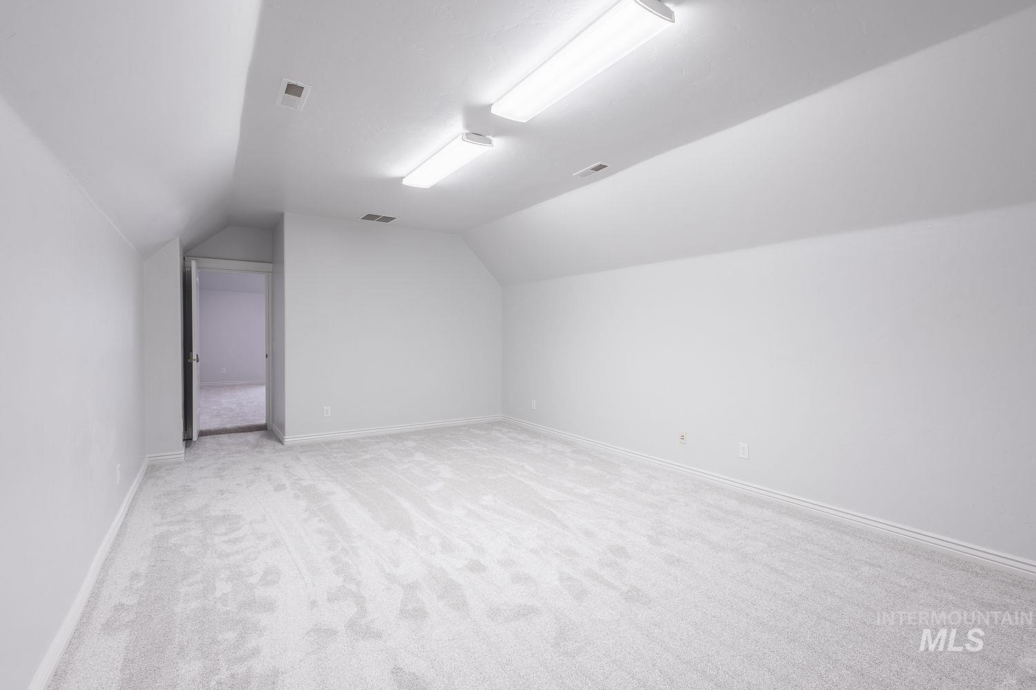 Additional living space featuring light carpet and lofted ceiling