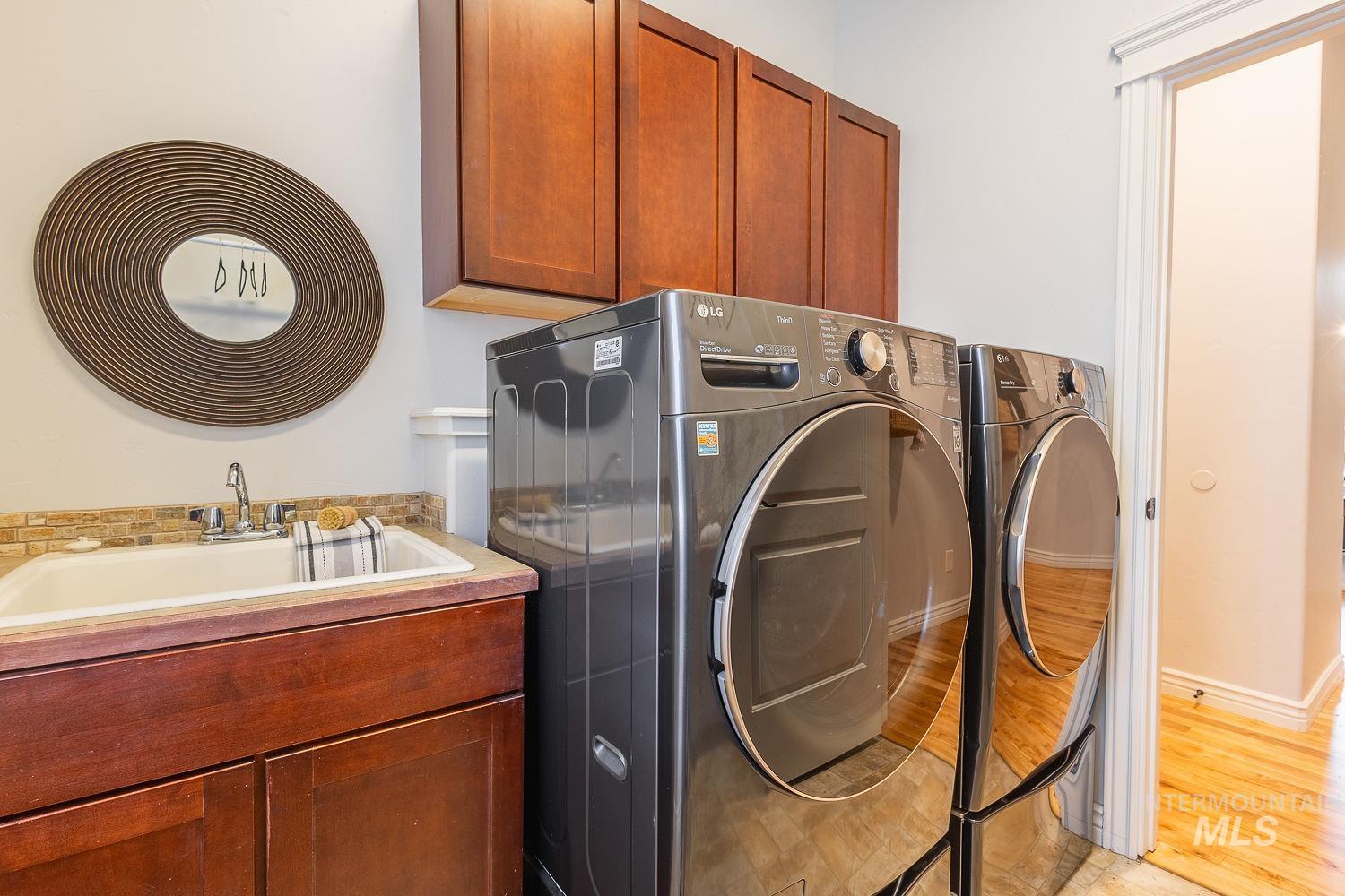 Laundry area featuring light wood finished floors, cabinet space, and washer and dryer