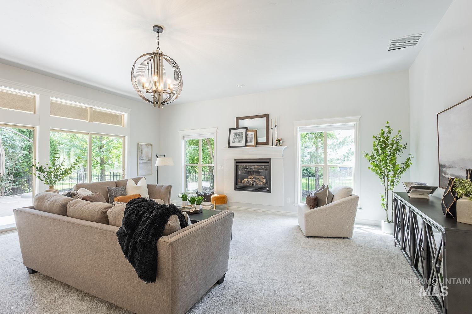 Living room featuring light colored carpet, a glass covered fireplace, and a chandelier