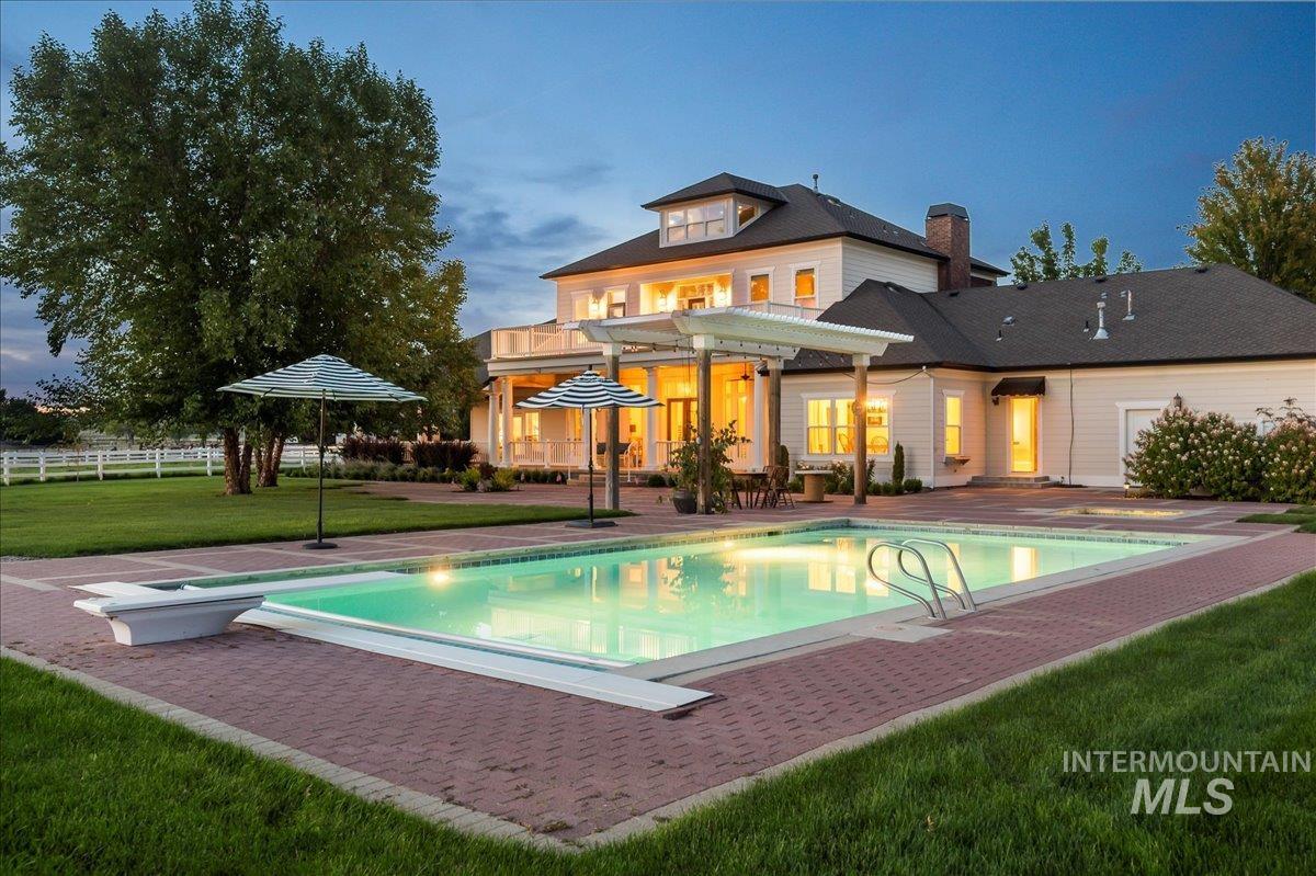 Back of house featuring a patio area, a yard, a chimney, and a balcony