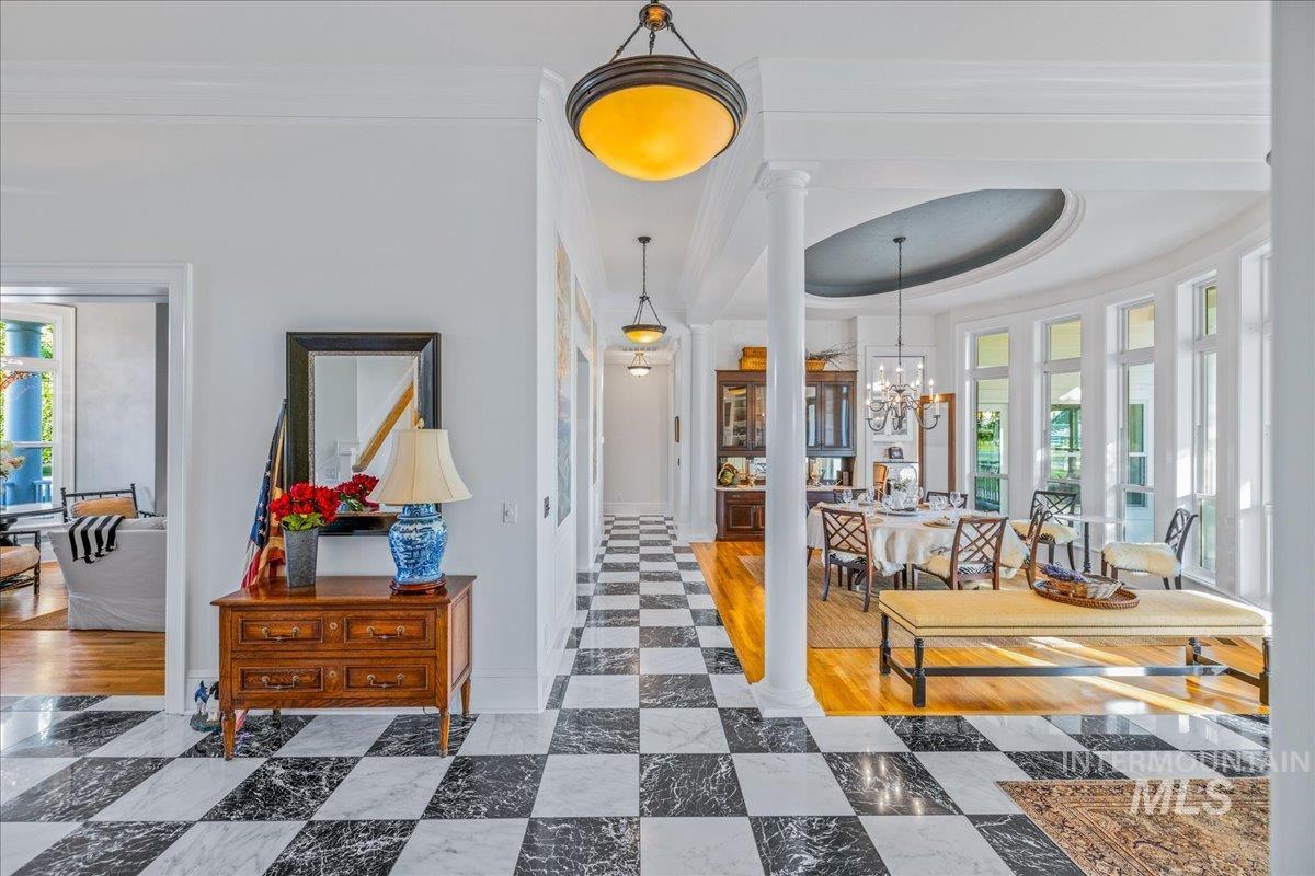 Hallway featuring healthy amount of natural light, a tray ceiling, crown molding, and a chandelier