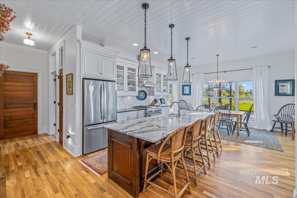 Kitchen with glass insert cabinets, appliances with stainless steel finishes, a kitchen bar, dark stone countertops, and wooden ceiling