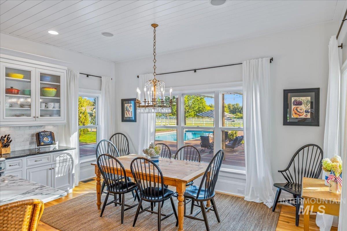 Dining space featuring light wood-type flooring, healthy amount of natural light, a chandelier, wood ceiling, and recessed lighting
