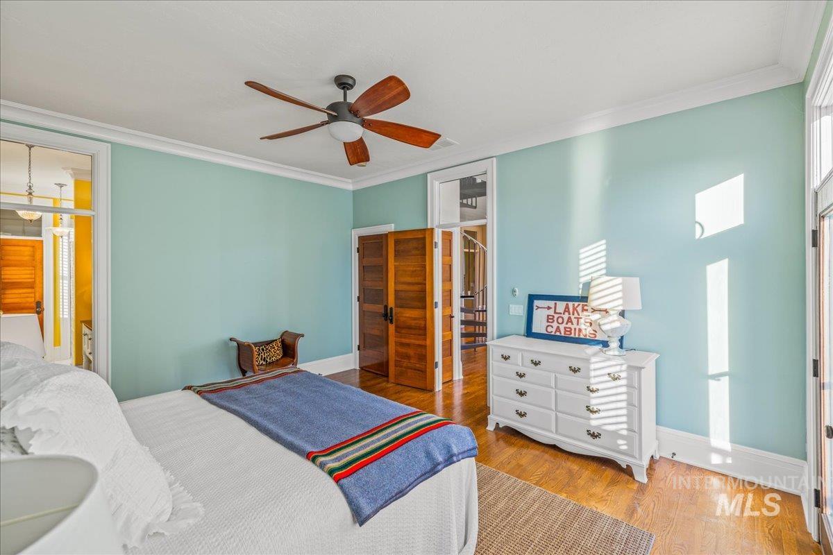 Bedroom featuring crown molding, light wood-style floors, a closet, a ceiling fan, and ensuite bath