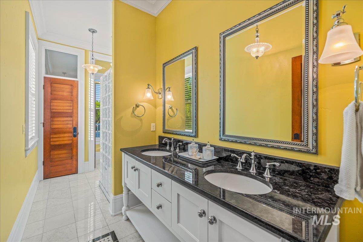 Bathroom featuring light tile patterned floors, double vanity, and crown molding