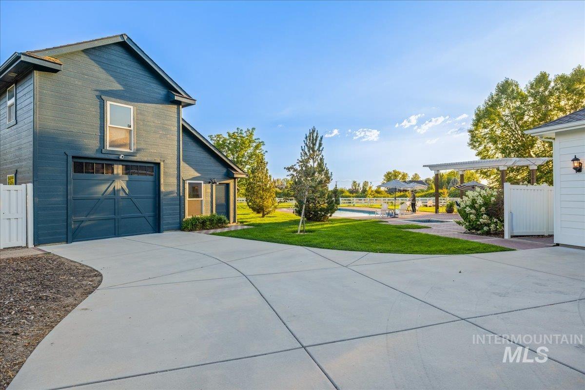 View of property exterior featuring a yard, concrete driveway, a patio area, and an attached garage