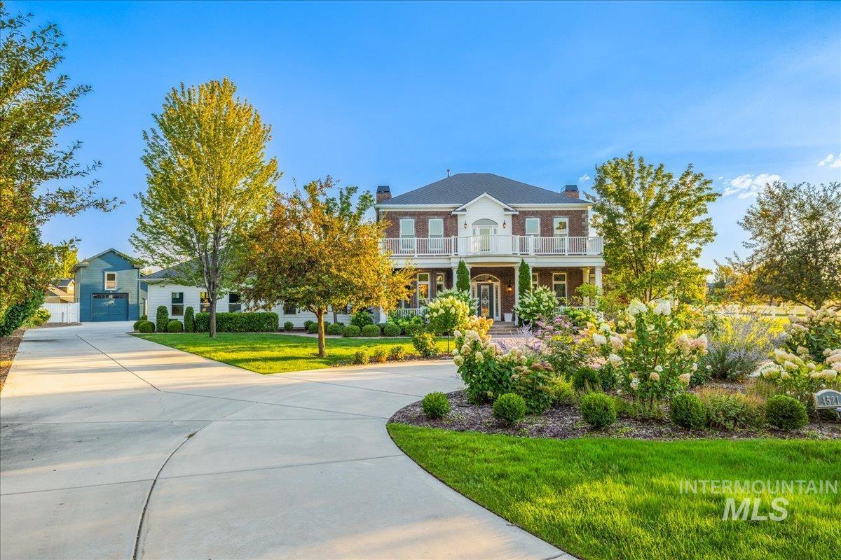 View of front of property with a chimney, a front lawn, driveway, and covered porch