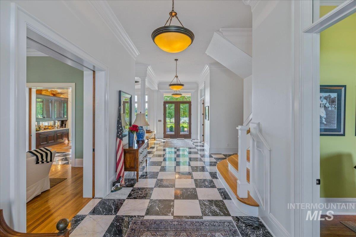 Hall featuring french doors, ornamental molding, wood finished floors, and stairway