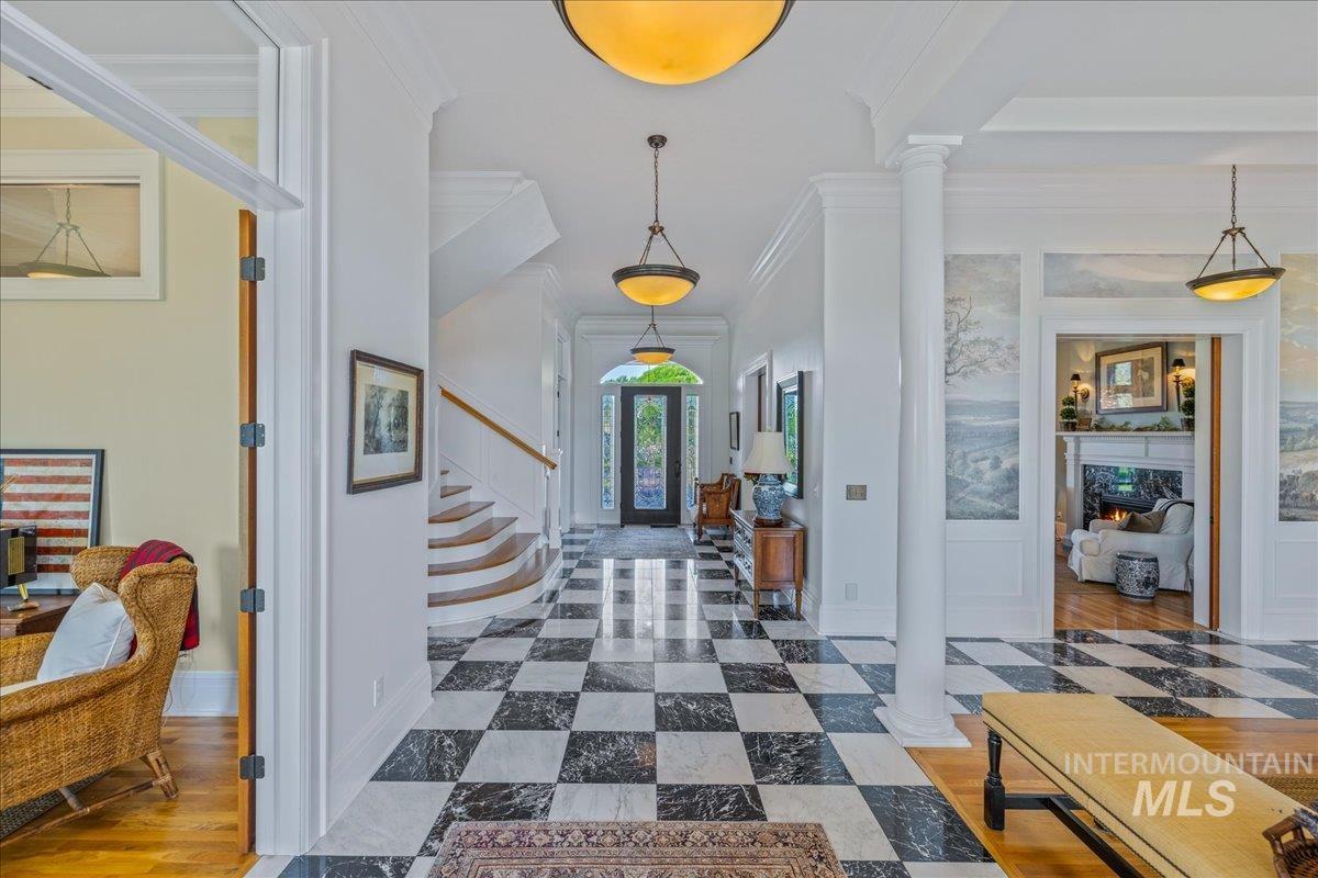 Foyer entrance featuring crown molding, decorative columns, and inlaid floor details
