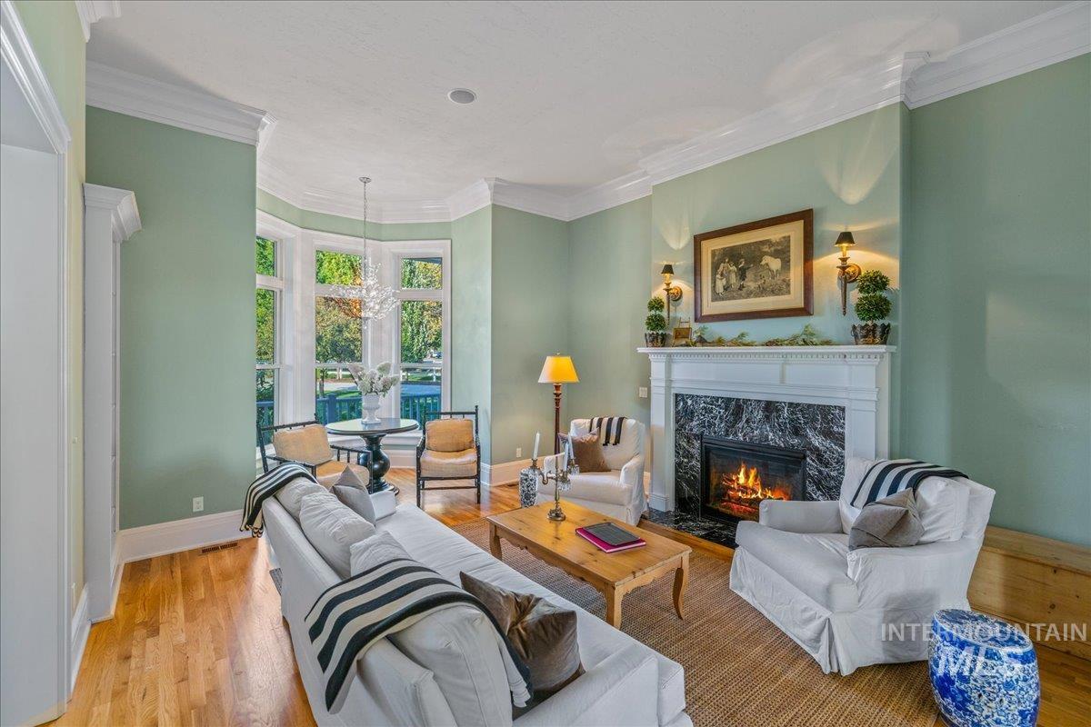 Living area featuring crown molding, wood finished floors, a premium fireplace, and a chandelier