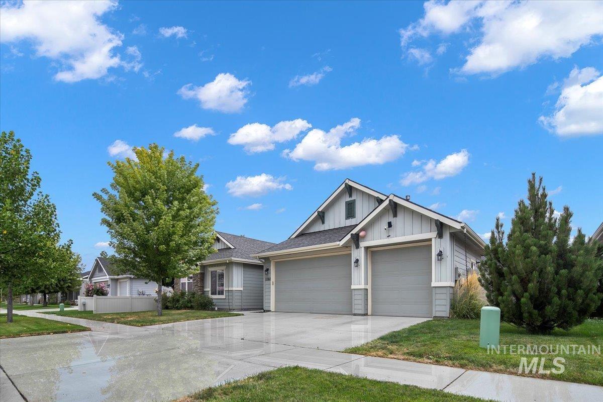 View of front of home featuring board and batten siding, a front yard, concrete driveway, and a garage