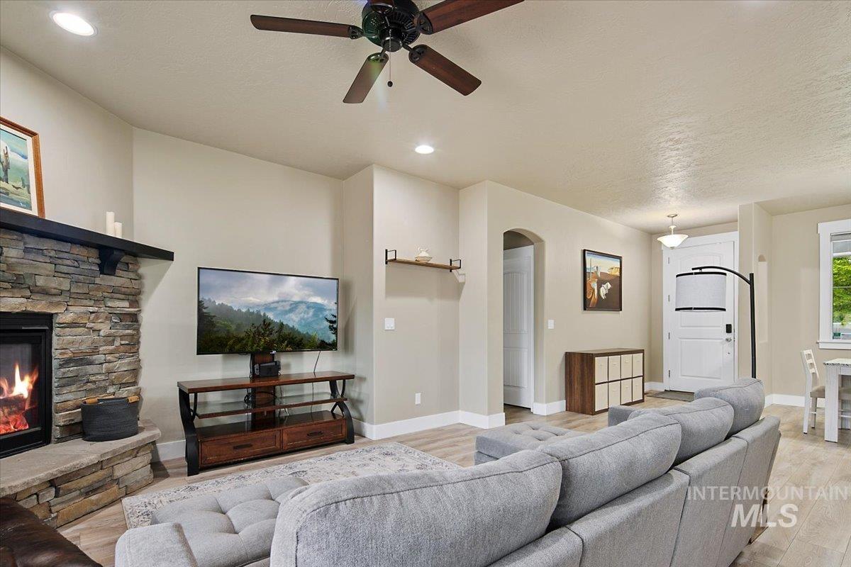 Living room with light wood finished floors, ceiling fan, recessed lighting, a fireplace, and a textured ceiling