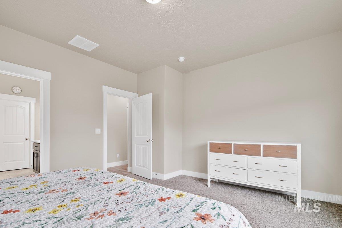 Bedroom with light colored carpet and a textured ceiling
