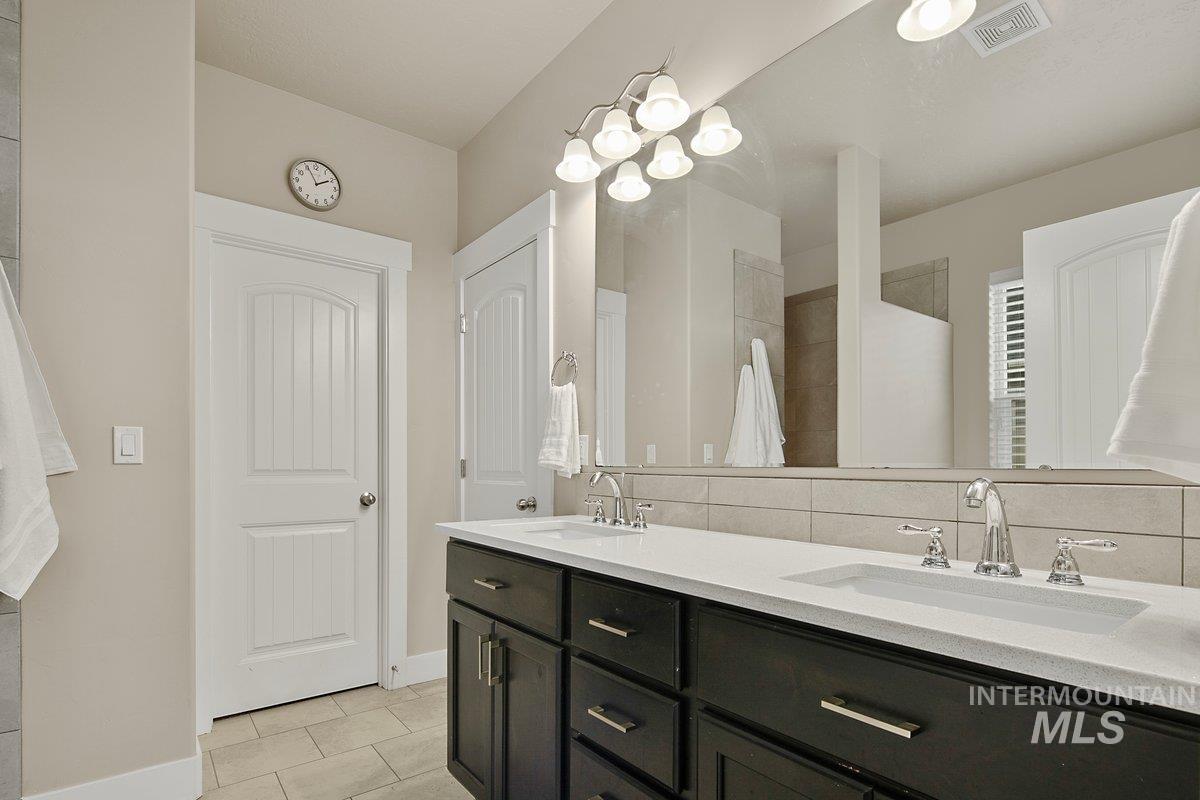 Bathroom with light tile patterned flooring, double vanity, and tasteful backsplash