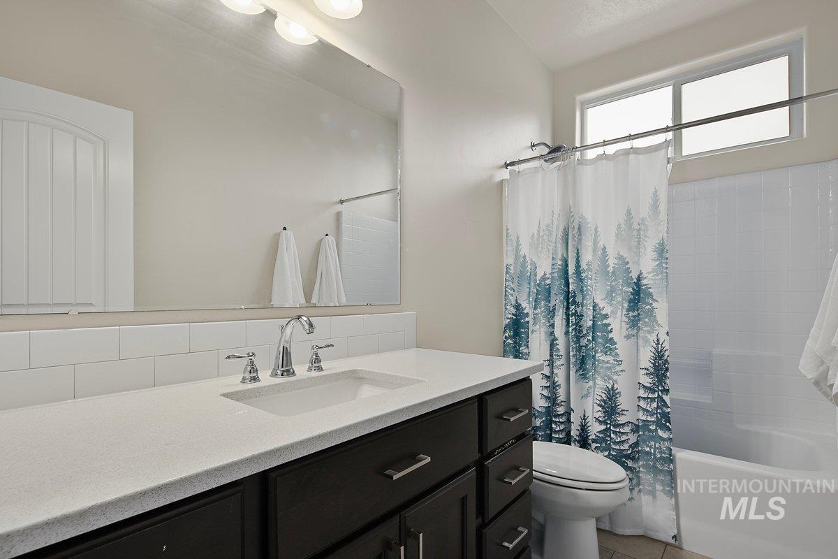 Full bathroom featuring shower / bath combo, vanity, backsplash, and light tile patterned flooring
