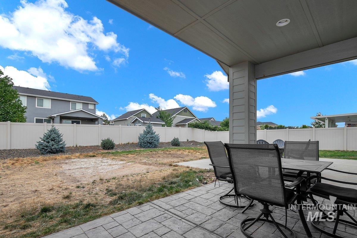 Fenced backyard featuring a patio, outdoor dining space, and a residential view