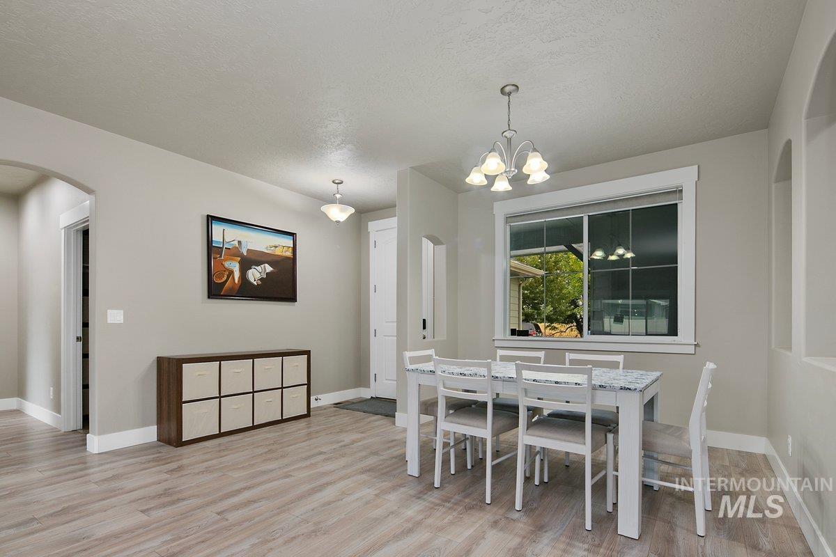 Dining space featuring arched walkways, a textured ceiling, light wood-style floors, and a chandelier