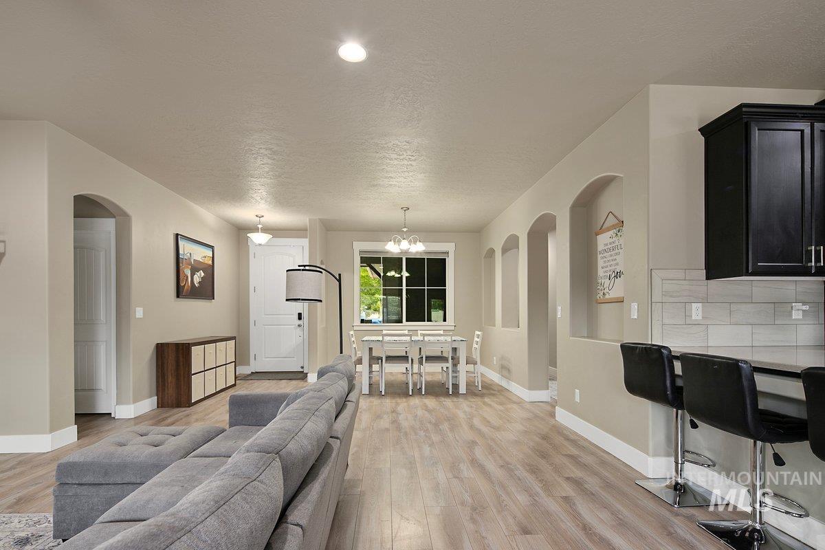 Living room featuring arched walkways, a textured ceiling, light wood-style floors, and a chandelier