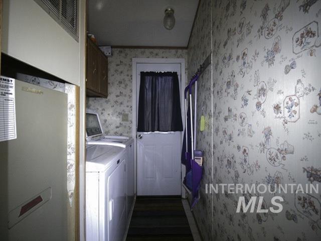 Washroom featuring cabinet space, dark wood-style flooring, independent washer and dryer, wallpapered walls, and a heating unit