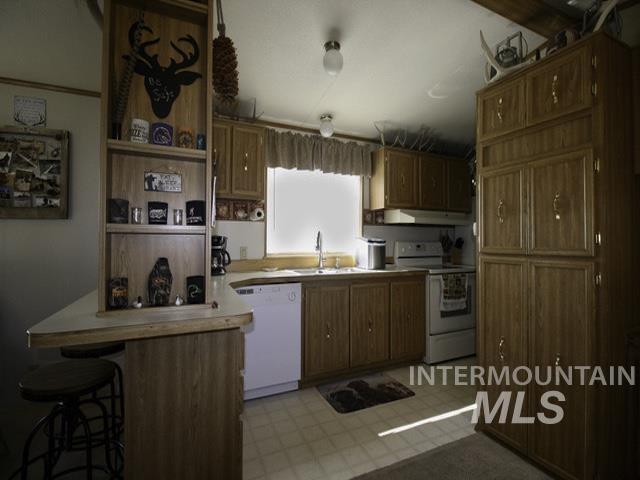 Kitchen with a peninsula, white appliances, a kitchen breakfast bar, open shelves, and brown cabinetry
