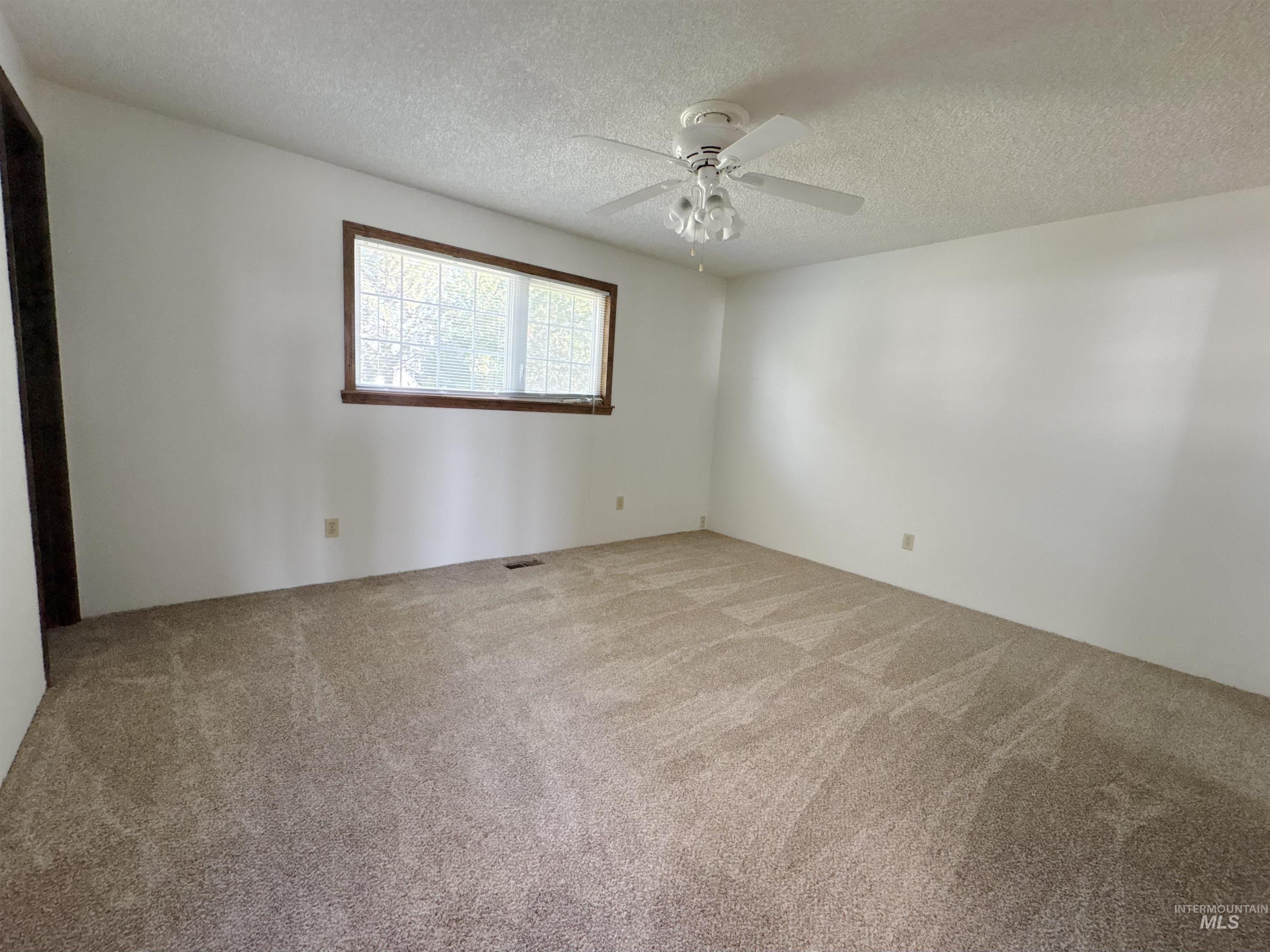 Carpeted spare room with a textured ceiling and a ceiling fan