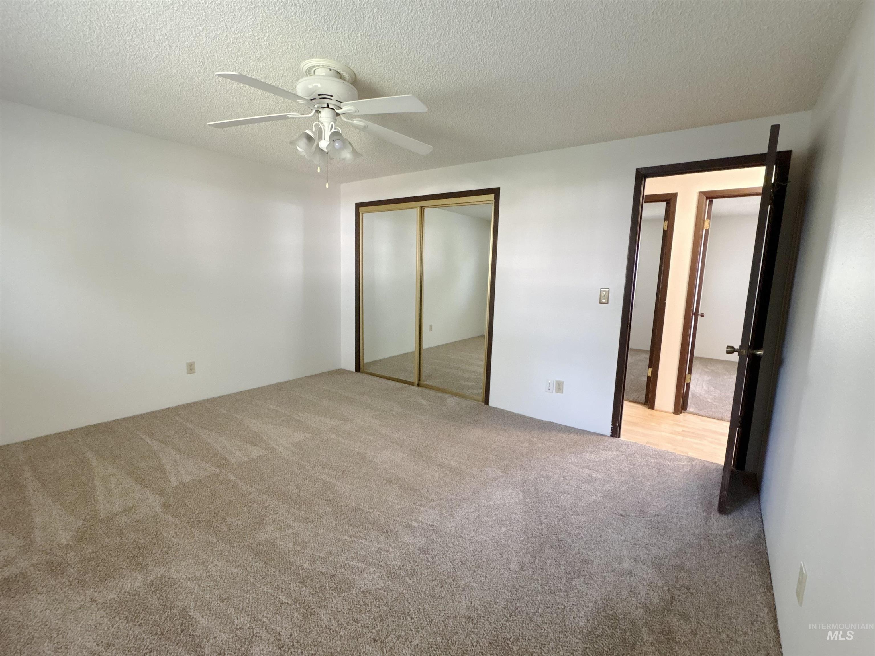 Unfurnished bedroom featuring carpet flooring, a textured ceiling, a closet, and ceiling fan